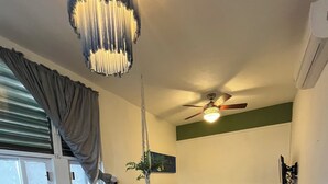 Una stanza compatta con un letto, un tavolino, una sedia, un divano e una ventola a soffitto.