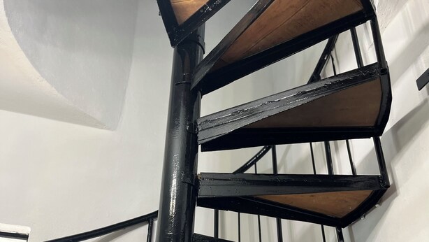 Una scala a chiocciola con ringhiere in metallo nero e gradini in legno.