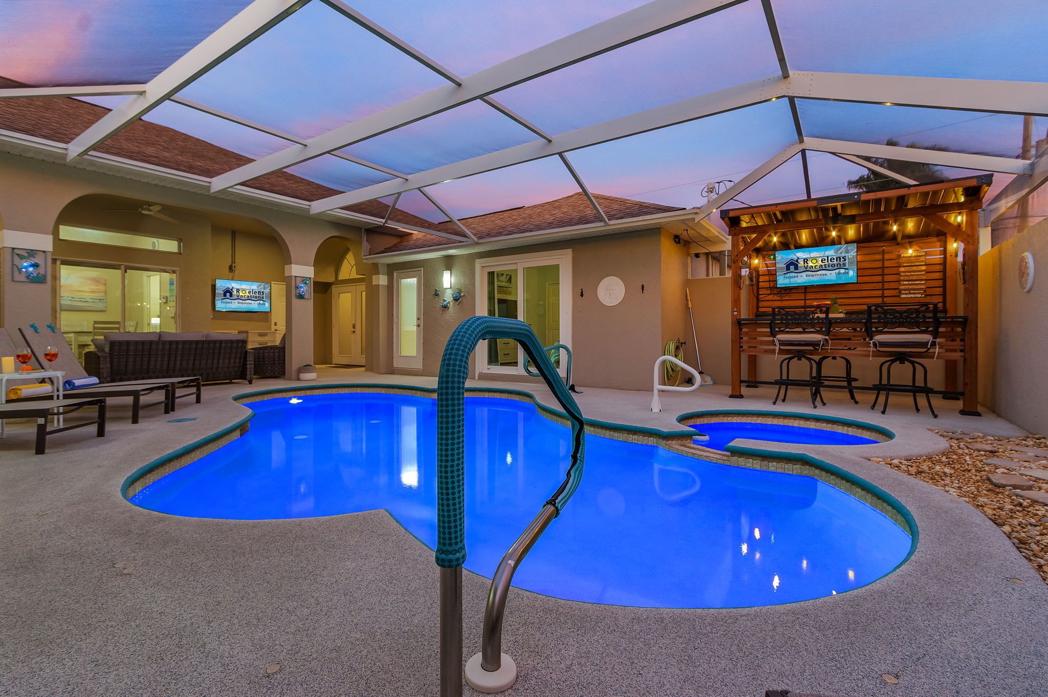 An indoor swimming pool with a glass ceiling, lounge chairs, and a bar area.