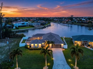 A waterfront property with a house, a dock, and a river. - Waterfront Bliss with Pool & Spa – Your Perfect Escape Awaits - Sunset Cove - Roelens (Cape Coral)