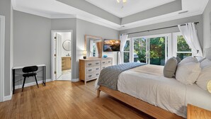 Un dormitorio con cama, escritorio, cómoda y un ventanal con cortinas.