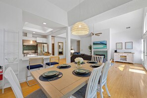 Een moderne eethoek met een houten tafel voor zes personen, witte stoelen en een kroonluchter.