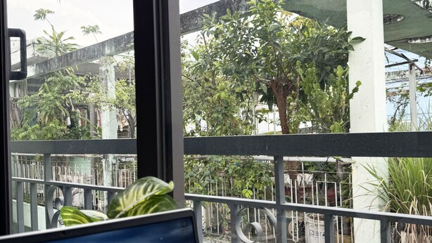 Una computadora portátil en un balcón con vistas a un edificio y follaje.