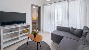 En moderne stue med et fladskærms-tv, en grå sofa, et træbord og en reol.