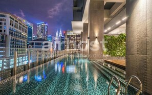 A modern hotel pool with a cityscape view, featuring a glass barrier and a reflection pool. - Anggun Residence KLCC by Airhost (Kuala Lumpur)