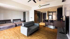 Una habitación de hotel moderna con dos camas, un sofá, una zona de cocina y un televisor.