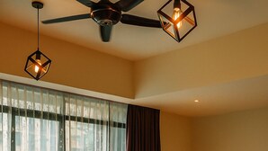 Una habitación de hotel moderna con sofá, una mesa redonda, cama y ventilador de techo.
