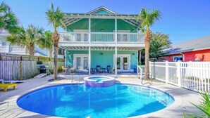 Ein zweistöckiges Haus mit Swimmingpool, überdachter Terrasse und eingezäunter Garten.