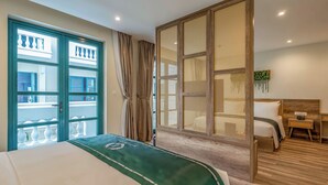 Une chambre d’hôtel avec un grand lit, une tête de lit en bois, un bureau et une vue dégagée sur l’extérieur grâce à une grande fenêtre.