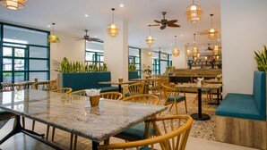 Un restaurant doté de nombreuses tables, de chaises, de ventilateurs de plafond et de luminaires suspendus.