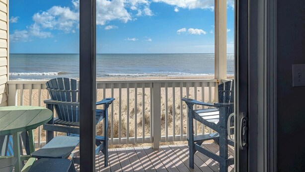 Ein Balkon mit Blick auf das Meer, einem Tisch und Stühlen.