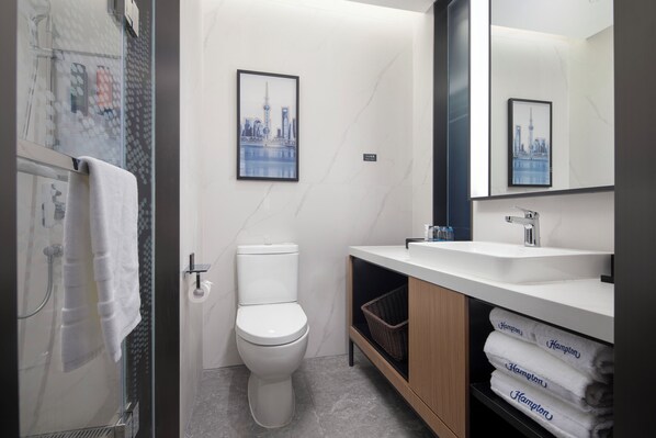 A modern bathroom with a toilet, sink, and glass shower enclosure. - Hampton by Hilton Shanghai North Bund Siping Road (Shanghai)