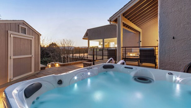 Un bain à remous dans un jardin, avec un patio couvert et un abri de jardin.