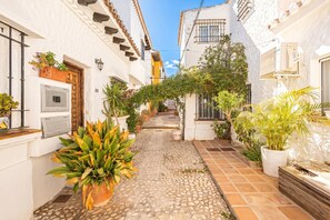 A narrow alleyway with white buildings, potted plants, and a tiled pathway. - La Casita De Pueblo Andaluz, Marbella, Spain (Marbella)
