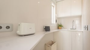 Eine moderne Küche mit weißen Schränken, einem eingebauten Toaster, einem kleinen Spülbecken und einem Fenster mit Tageslicht.