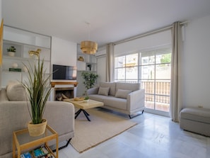Una sala de estar moderna con un sofá, una mesa de centro, un televisor y una chimenea.