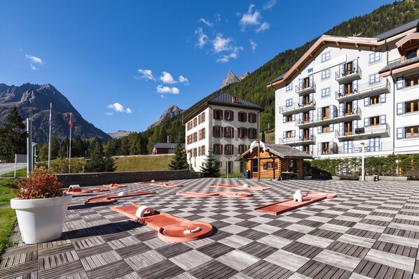 A hotel with a checkered deck, a mountain backdrop, and a building with balconies. - V Balme 15: Beside Ski Lift; Pool, Sauna & Gym, Vallorcine (Argentiere), France (Vallorcine (Argentiere))