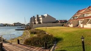 Ein Anwesen am Wasser mit moderner Architektur, einer Rasenfläche und einem Steg mit Booten.