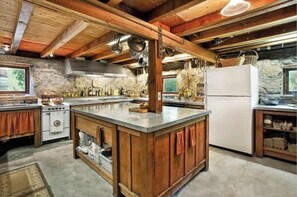 Eine rustikale Küche mit einer zentralen Kochinsel, Holzschränken und einer Wand aus Stein.