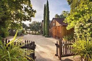 A rustic wooden barn with a gravel driveway and a wooden fence. - La Buona Stella Napa Valley (Saint Helena)