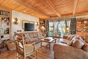 A cozy living room with a wooden ceiling, a television, and a fireplace.