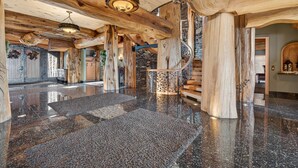 Un vestíbulo espacioso con piso de granito pulido, vigas de madera y una escalera central.
