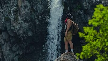 A person standing on a rock by a waterfall.