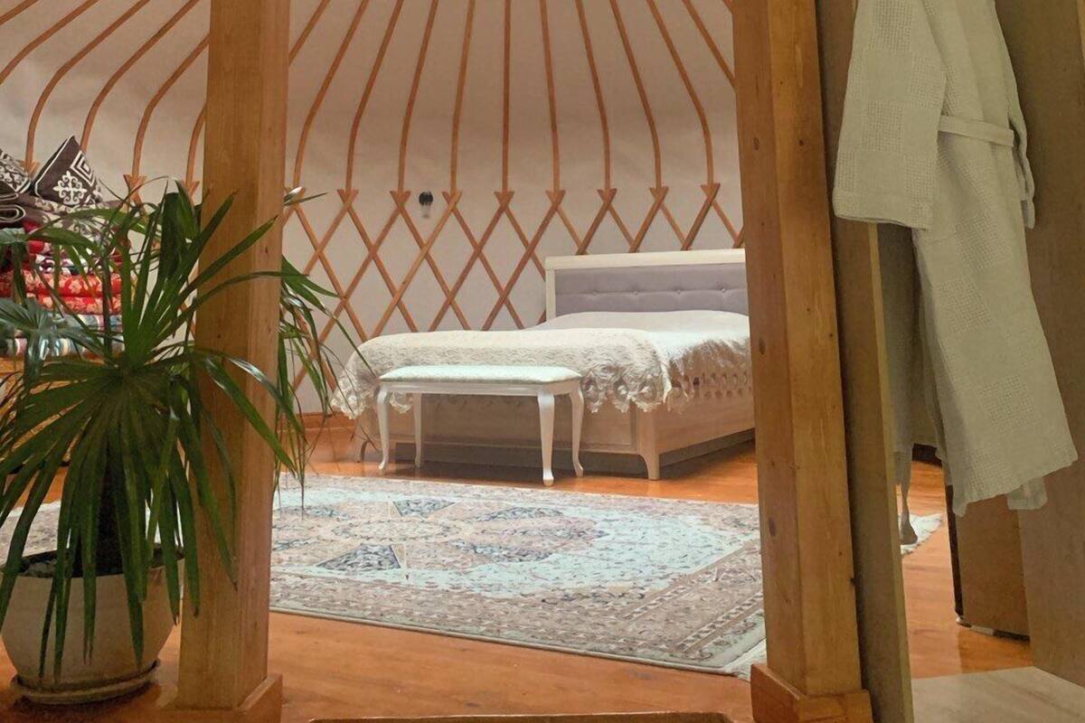 A cozy room with a circular skylight, a bed, a bench, and a hanging robe.