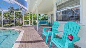 A pool area with turquoise chairs and a view of palm trees. - Villa Samba (Cape Coral)