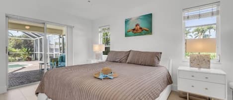 Un dormitorio con cama, mesita de noche, ventana con persianas y vistas al exterior.
