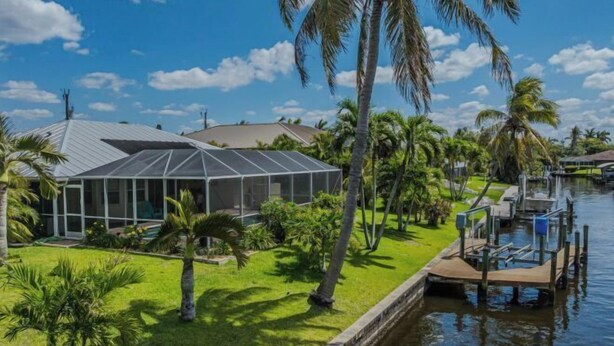A modern house with a glass conservatory, a dock, and a canal. - Villa Samba (Cape Coral)