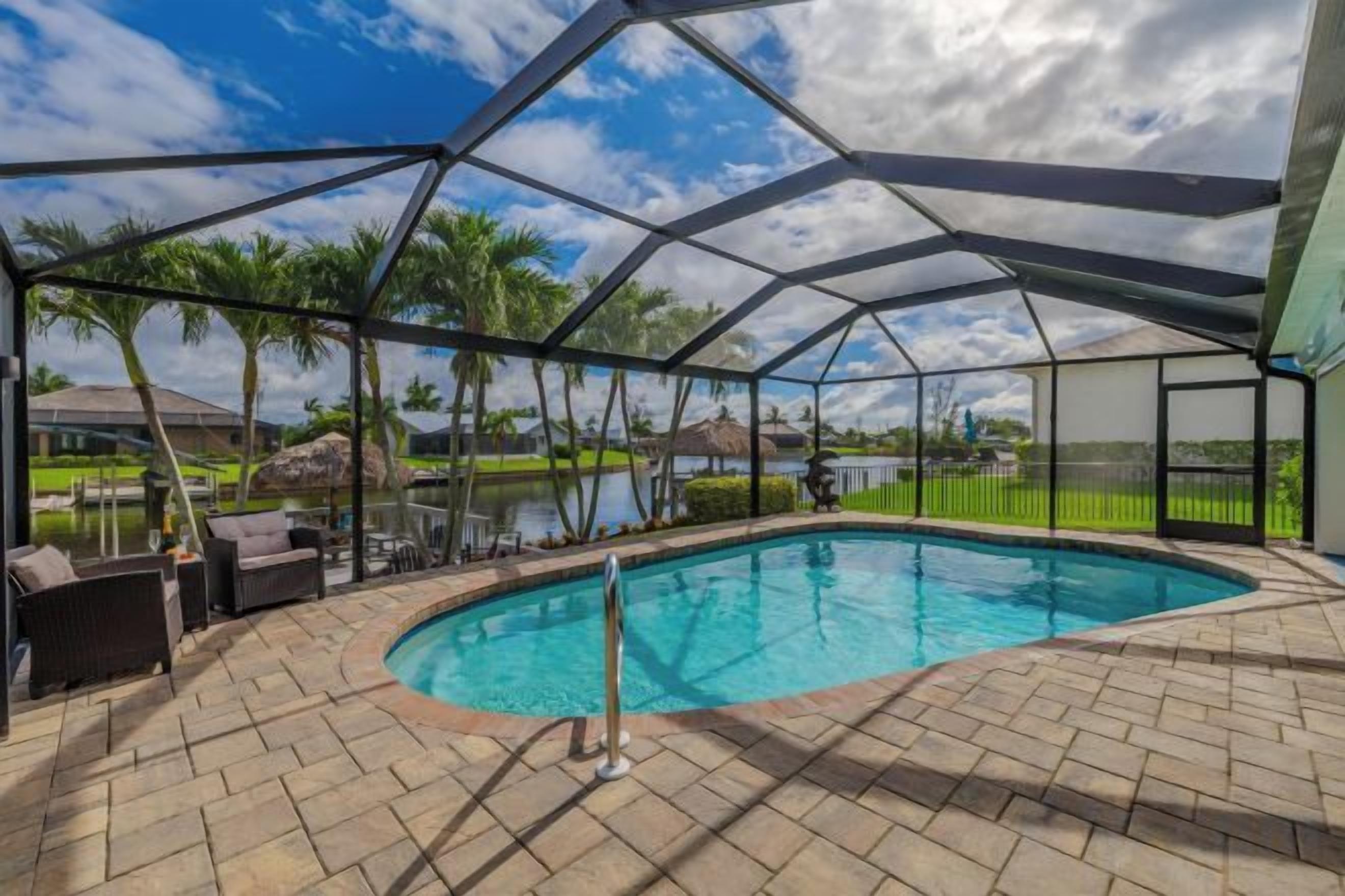 A covered outdoor swimming pool with a clear view of the surrounding landscape, including a body of water and greenery.