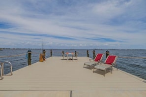 A pier with a table and chairs, a rope barrier, and a view of the water. - SeaBreeze Vista (Cape Coral)