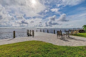 A waterfront promenade with a paved walkway, benches, and a railing overlooking the water. - SeaBreeze Vista (Cape Coral)