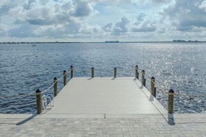 A wooden pier extending into a body of water with a clear sky above. - SeaBreeze Vista (Cape Coral)