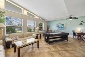 Amplia sala de estar con mesa de billar, sofá y una mesa de centro.