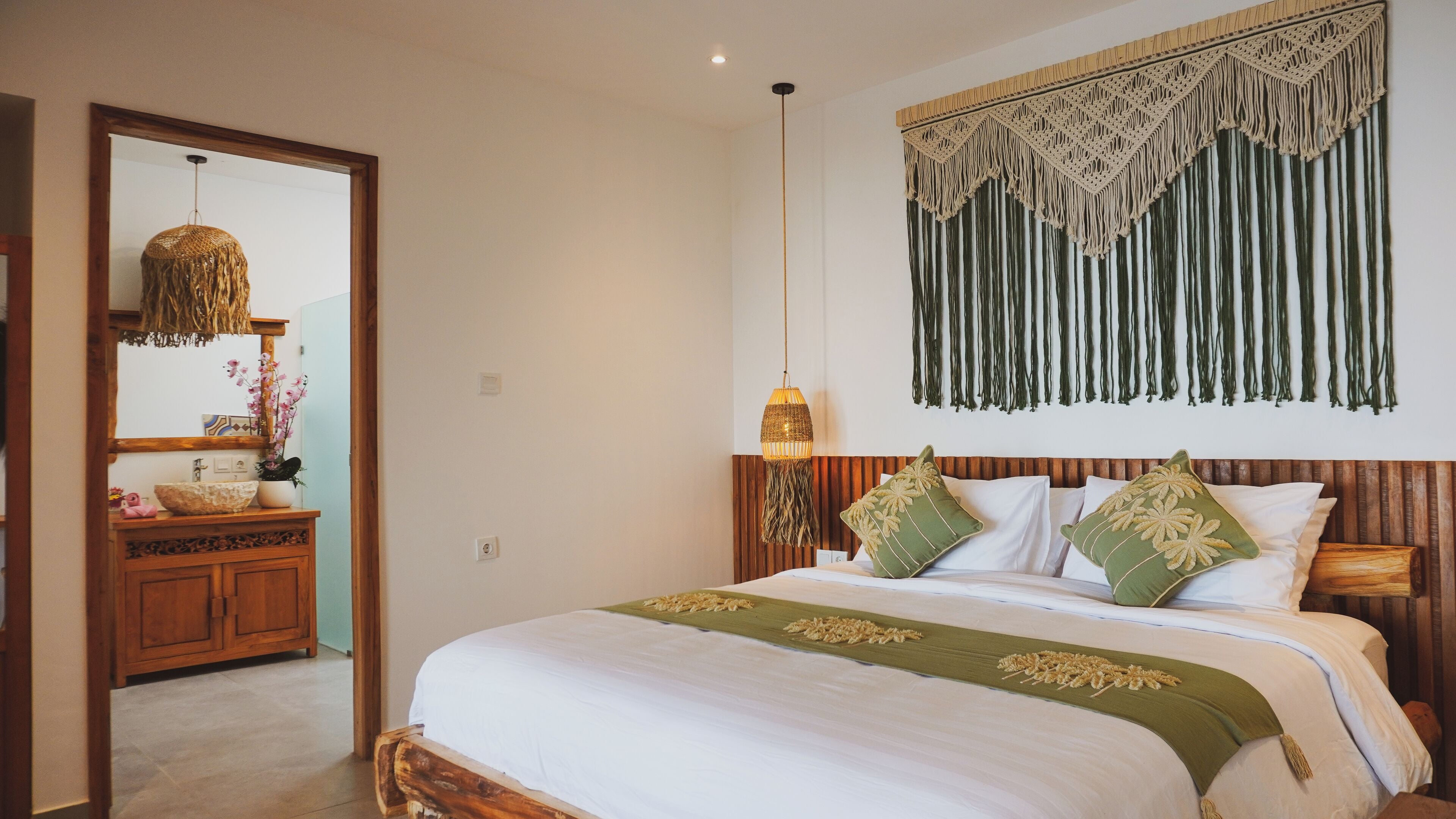 A bedroom with a large bed, wooden headboard, and a macramé wall hanging.