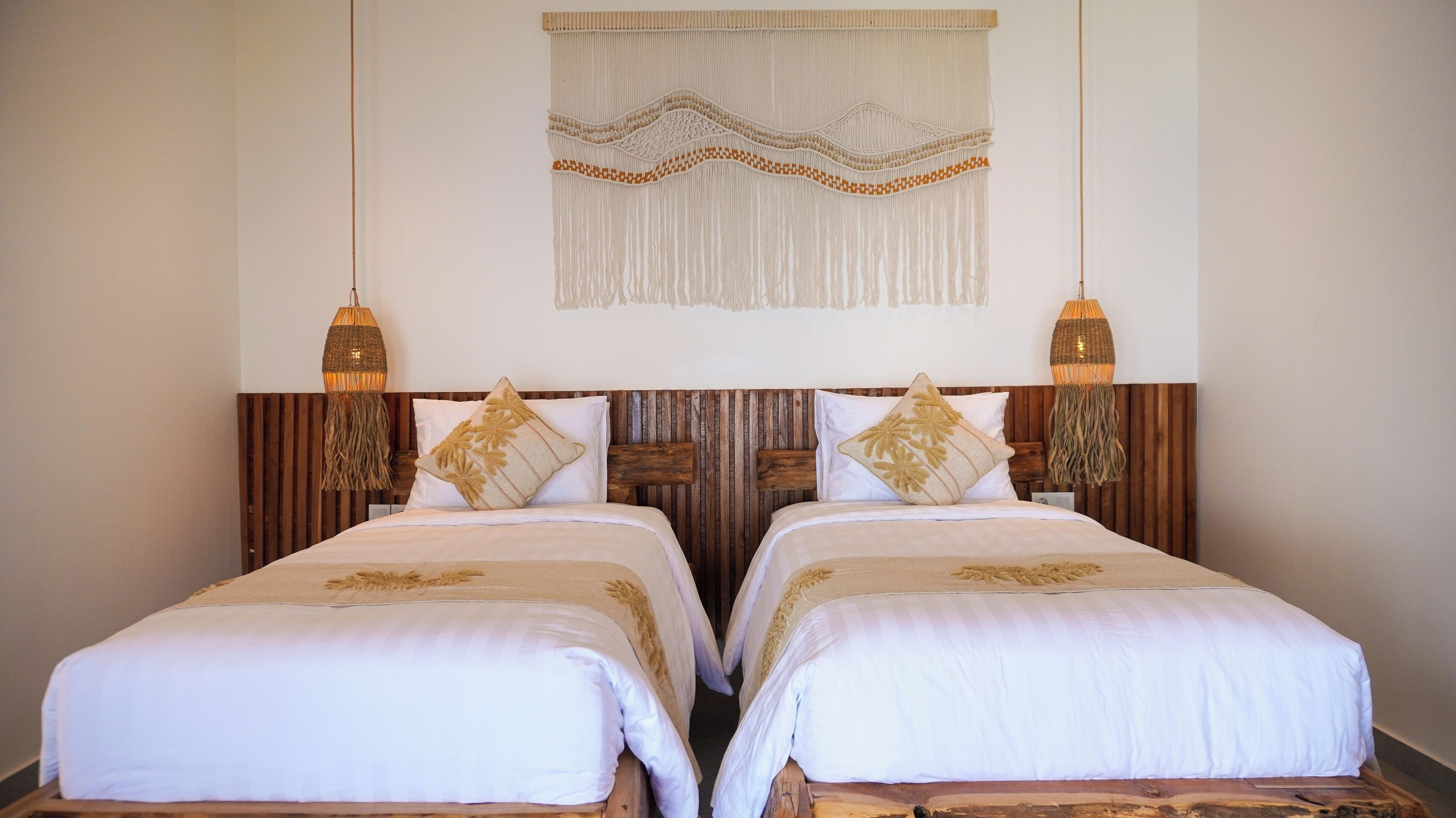 A double bed room with wooden headboard, two bedside lamps, and a decorative wall hanging.