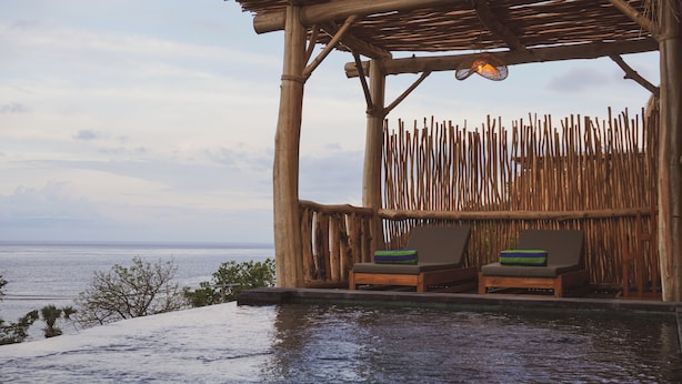 A wooden structure with two lounge chairs and a view of the sea.