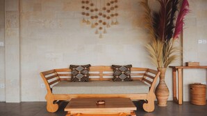 A wooden sofa with patterned cushions, a small wooden table, and a decorative wall hanging.