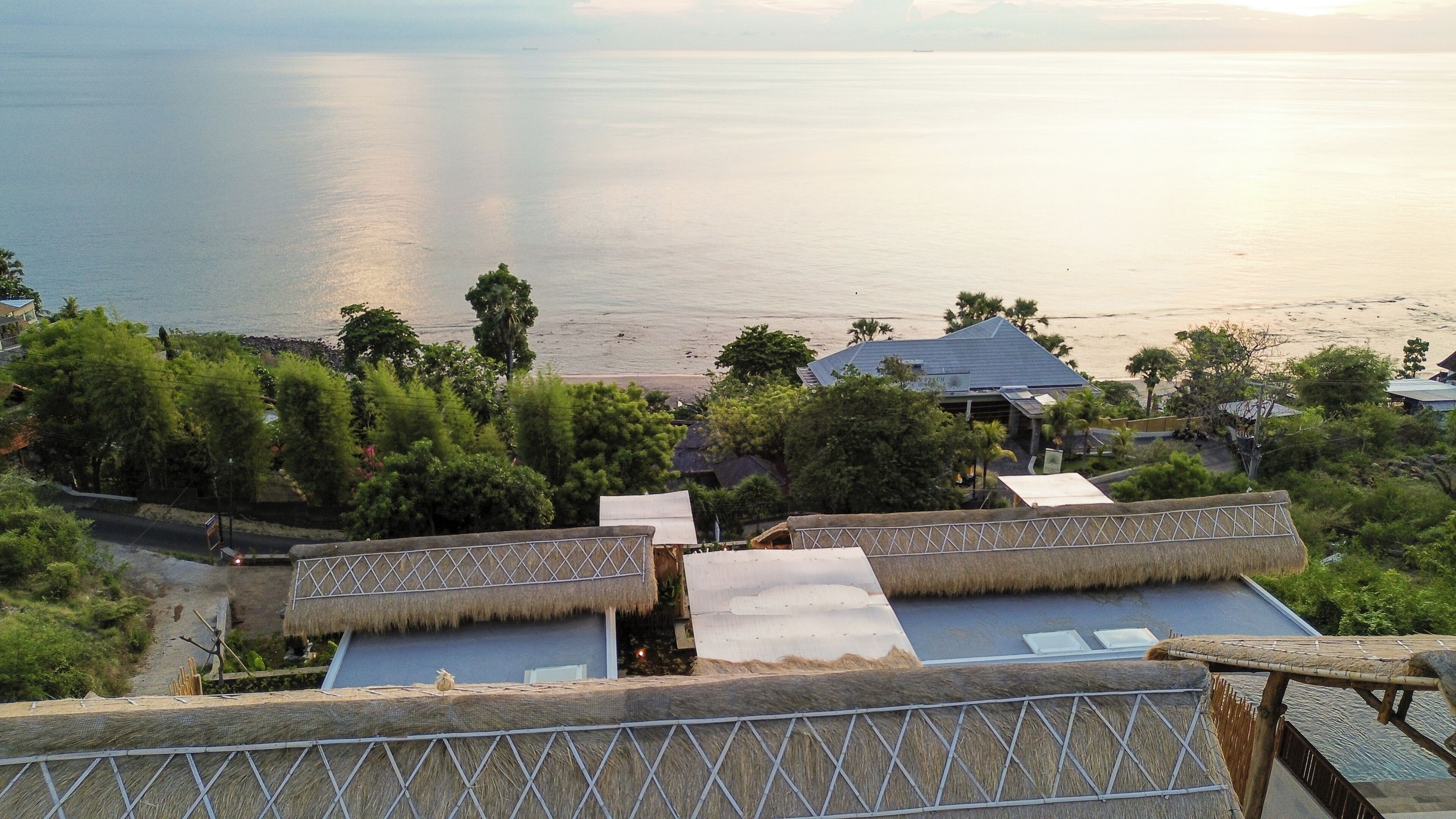 A coastal resort with thatched-roof structures, a beach, and a view of the sea.