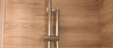 A shower with a modern design, featuring a rain shower head and a glass shelf.