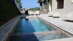 A rectangular swimming pool with clear water, surrounded by a tiled deck and white chairs. - ma-la studios Guimarães 302 (Guimarães)