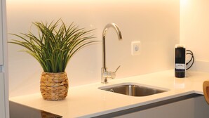A modern kitchen with a stainless steel sink, a woven plant pot, and a black appliance on the counter. - ma-la studios Guimarães 302 (Guimarães)