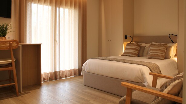 A bedroom with a bed, bedside tables, a desk, a chair, and a TV mounted on the wall. - ma-la studios Guimarães 302 (Guimarães)