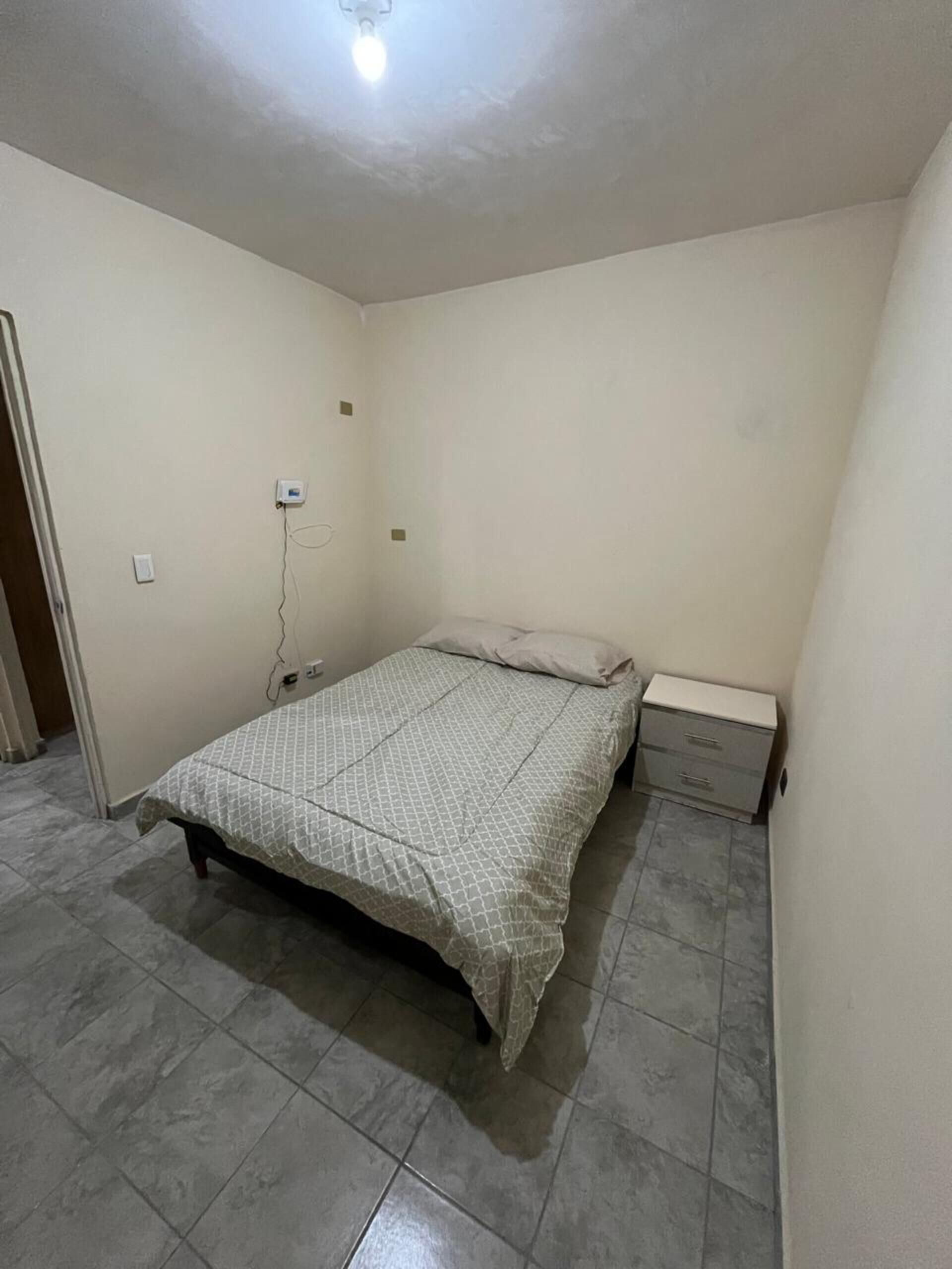 A bedroom with a bed, a nightstand, and a wall socket.