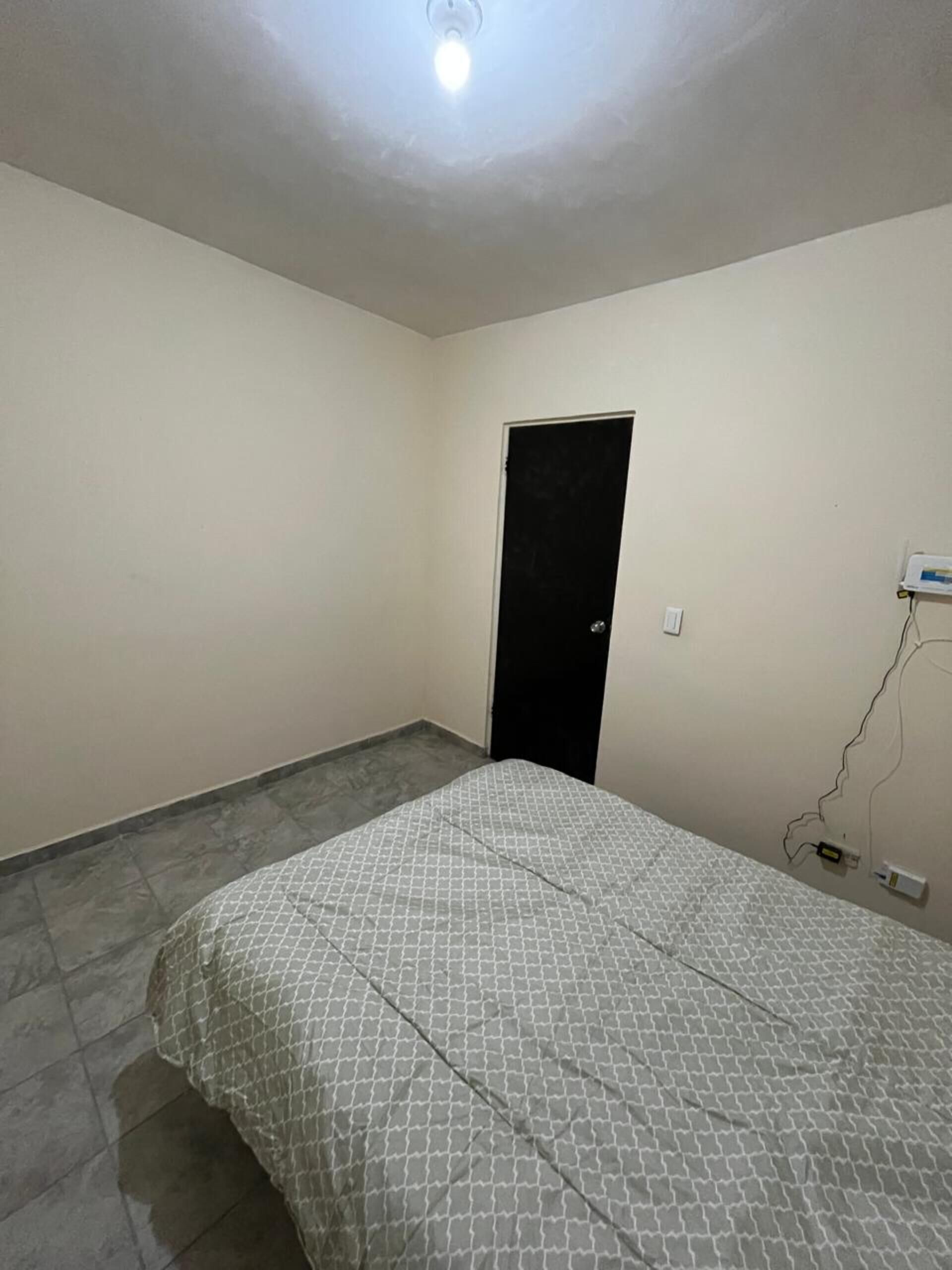 Une chambre à coucher avec un lit, une porte et une prise de courant.