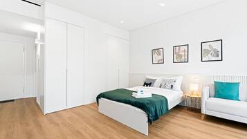 Una camera da letto moderna con un letto, un'armadio bianco e un comodino con una lampada.