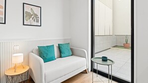 A modern room with a white sofa, teal cushions, a small round table, and a lamp. - GuestReady – Magnolia (Aveiro)