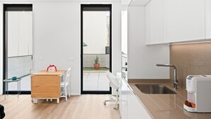 A modern kitchen with a sink, countertop, and a dining area with a table and chairs. - GuestReady – Magnolia (Aveiro)